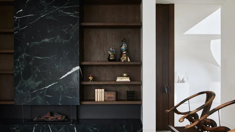 Black marble fireplace wall with built-in timber shelving